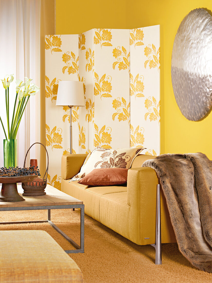 Room with yellow sofa, white folding screen, cushion and table