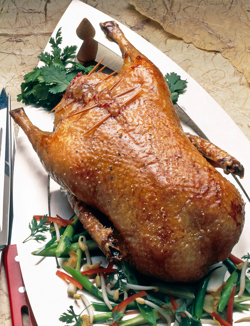 Close-up of roasted duck with cilantro, bean sprouts and pepper on plate