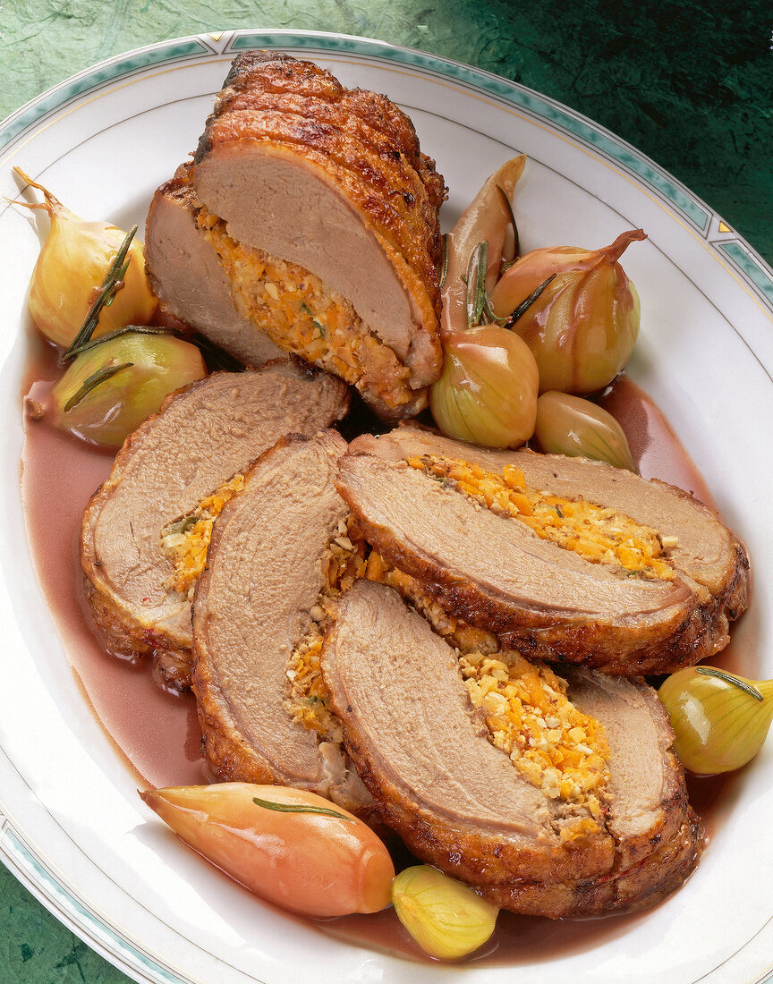 Close-up of stuffed duck breast with onion, carrot, apple and gravy in bowl