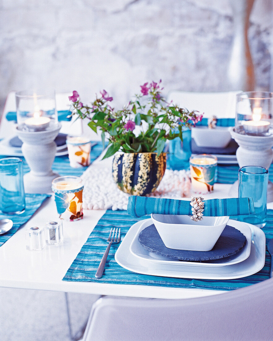 Table laid with blue-white plates, glasses, flower vase and table cloth