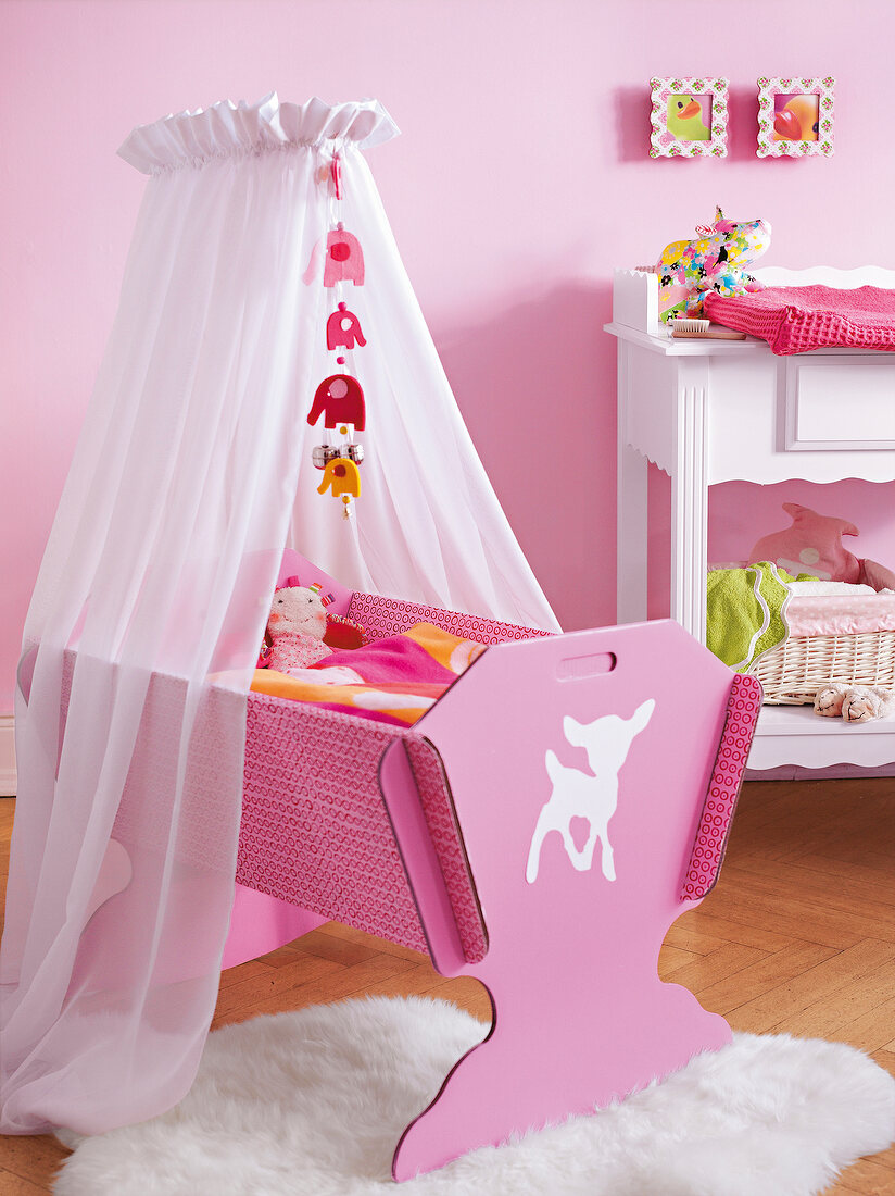 Children's room with pink cradle under canopy on fur rug