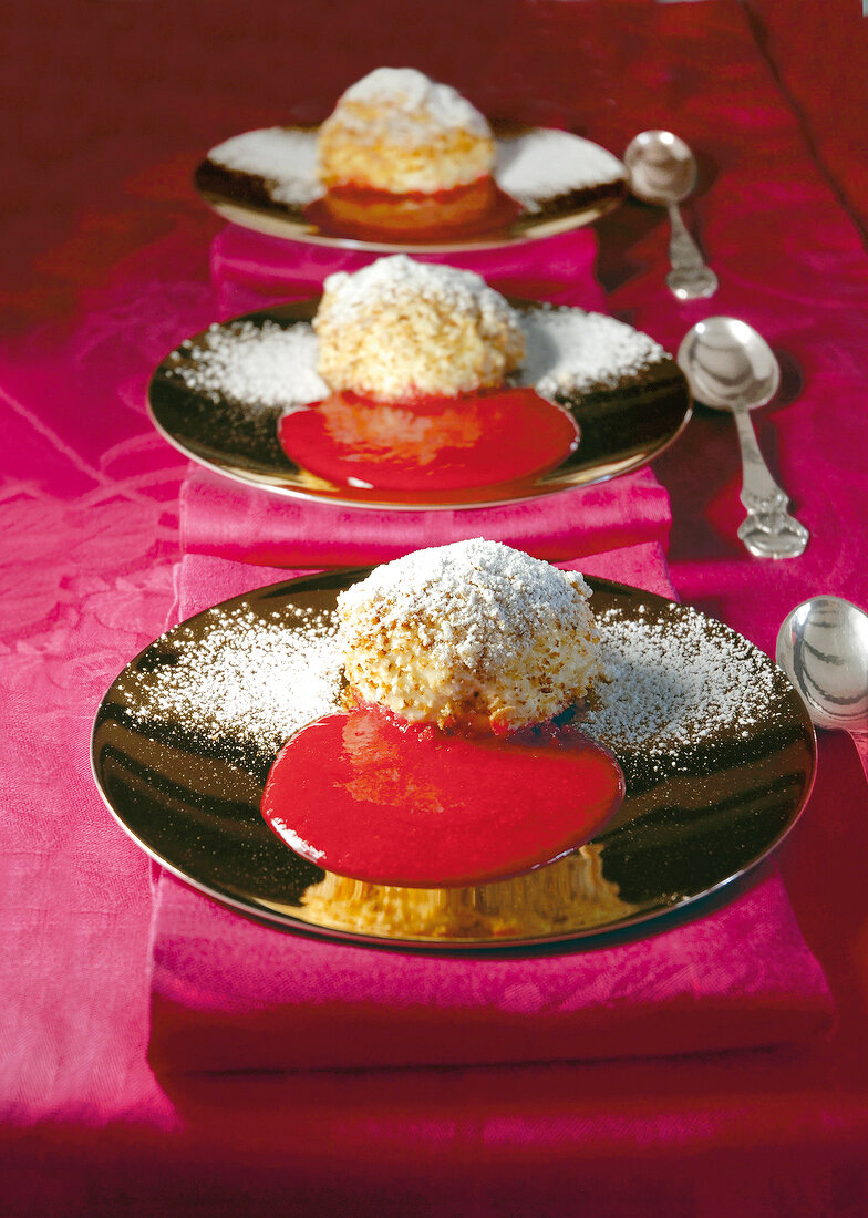 Curd cheese dumplings with apricot raspberry puree and icing sugar on plate