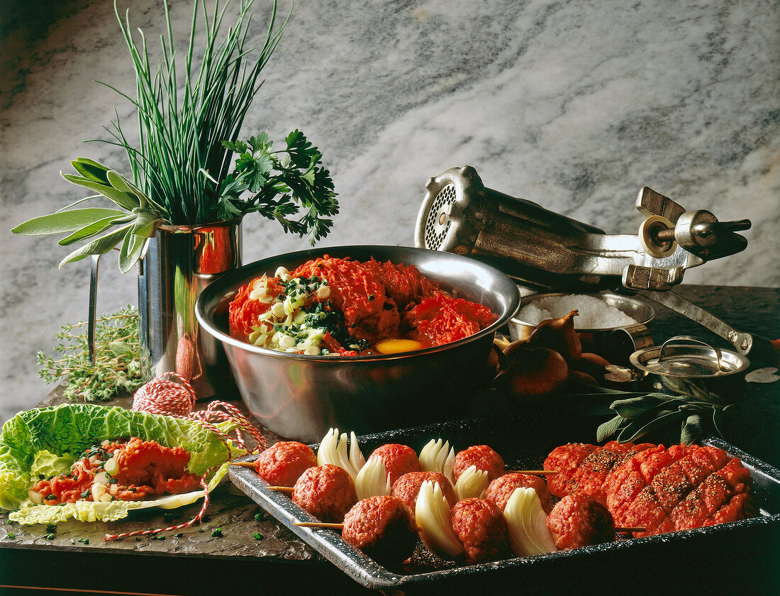 Herbs and meat skewers on tray - ingredients for dishes of minced meat