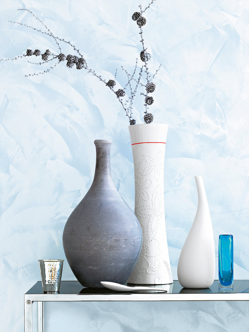 Versch. Vasen in Grau und Weiß, Zweig, Wand blau gespachtelt