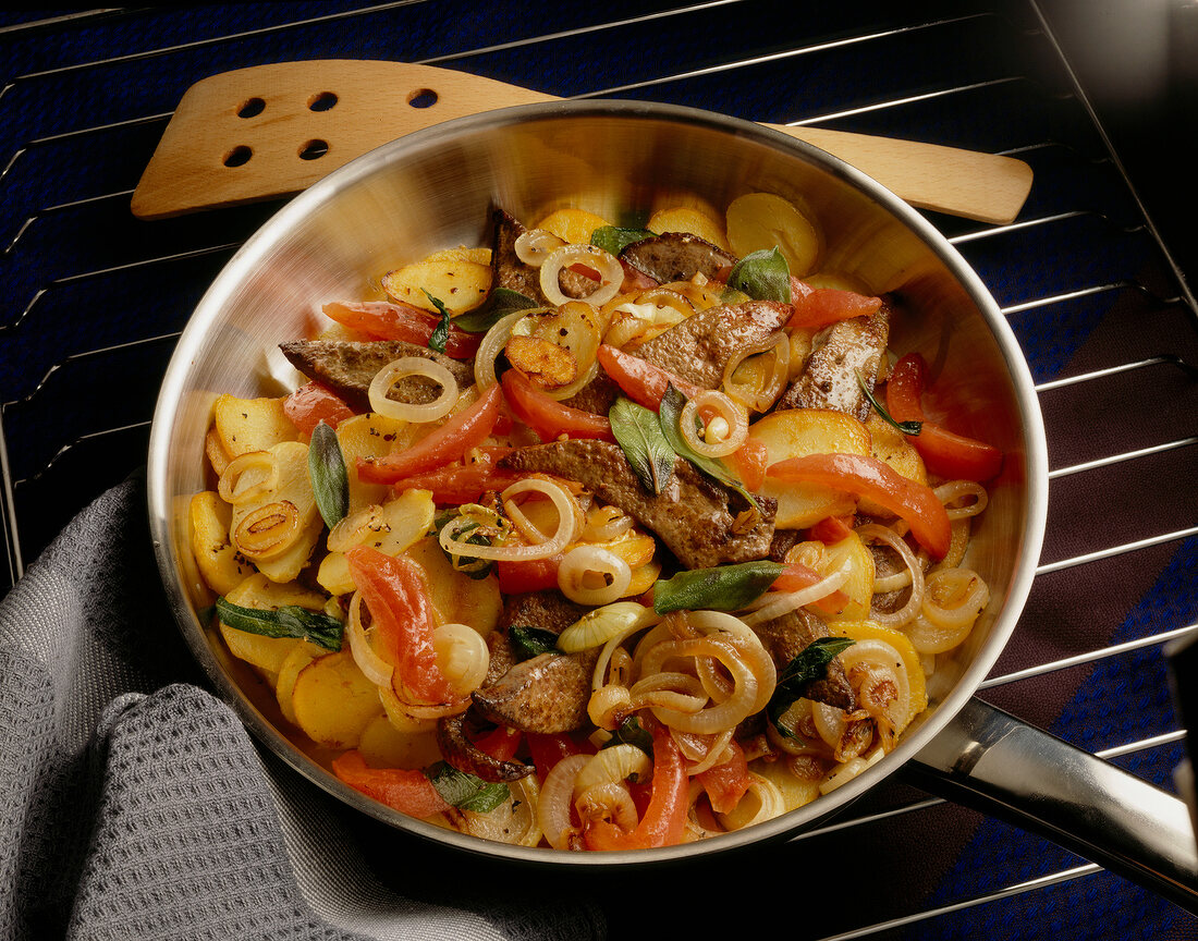 Potato with onions, tomatoes and sage leaves in pan