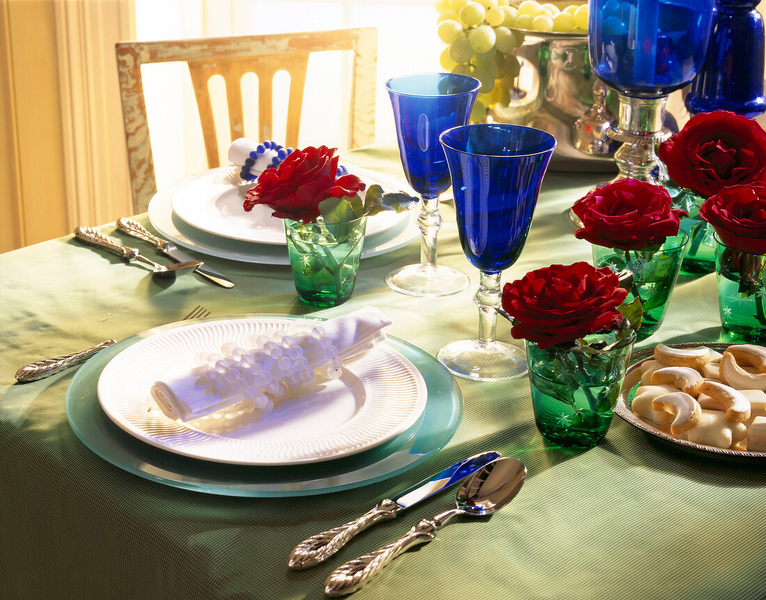 Table with dishes, blue and green glasses