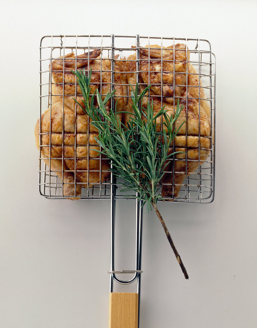 Chicken in grillrost with thyme sprigs on white background