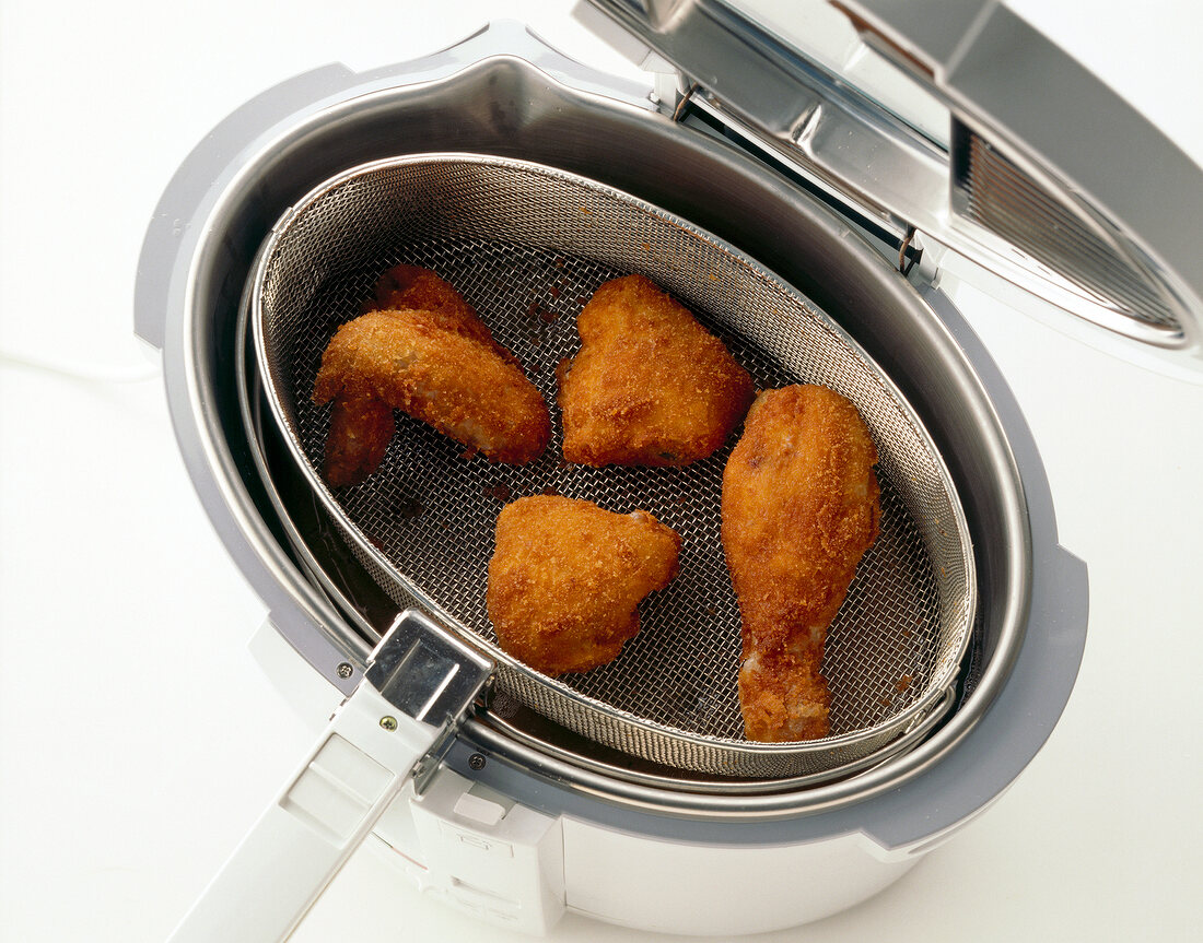 Close-up of chicken in strainer of deep fryer