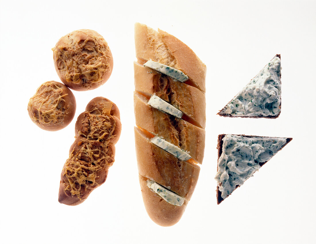 Baguette and slices with herb butter and homemade rolls on white background