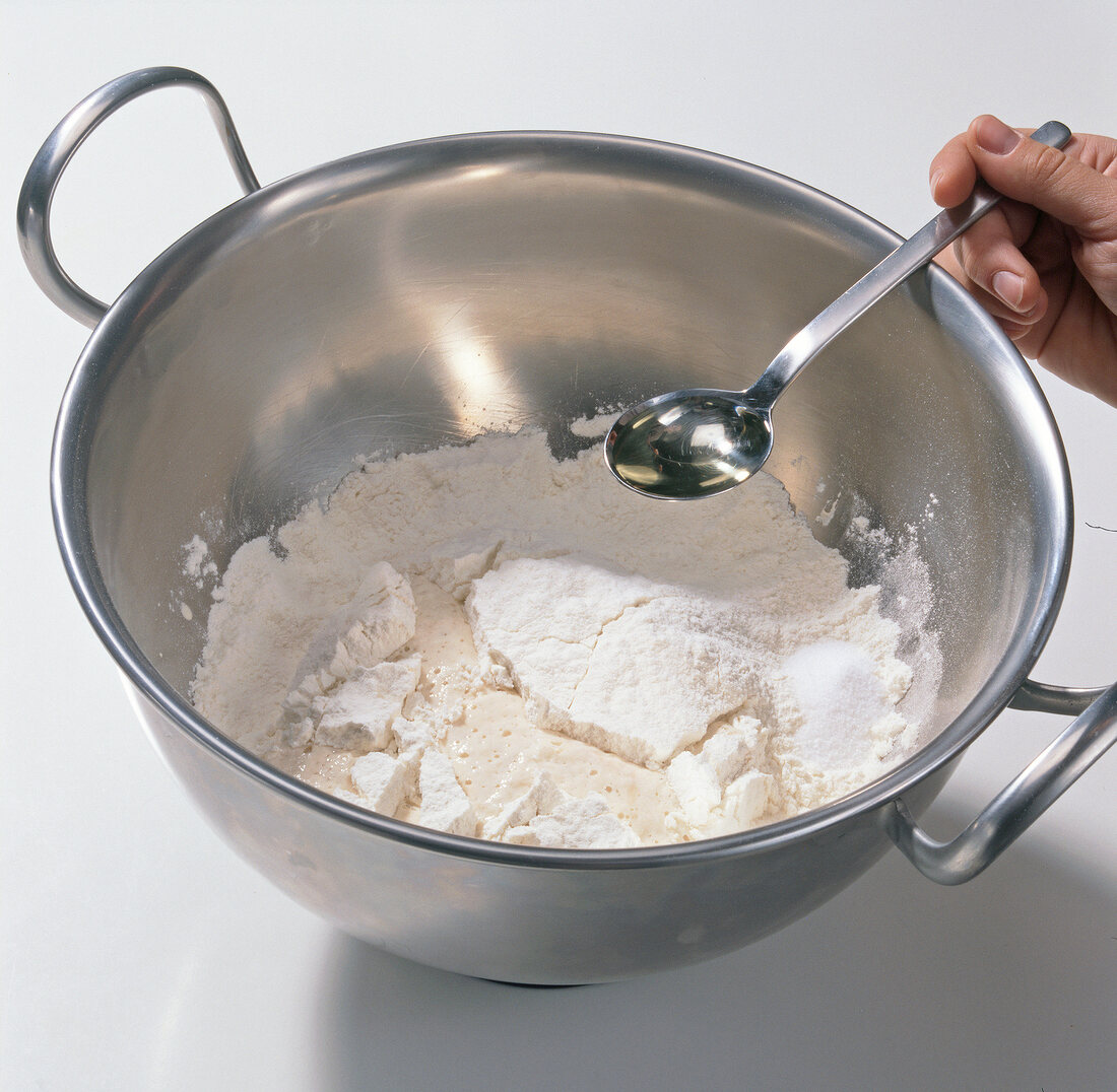 Adding oil to mixture of flour with water and yeast