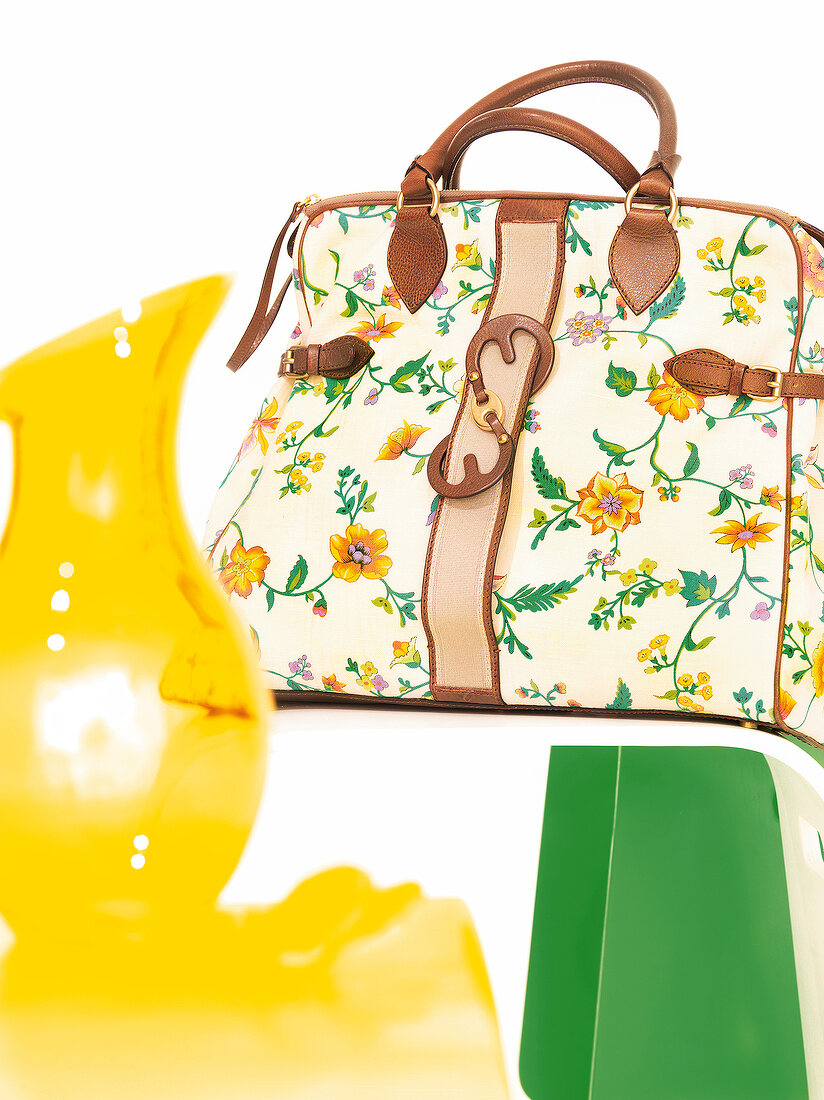 Tasche mit floralem Muster und braunen Lederakzenten, gelber Krug