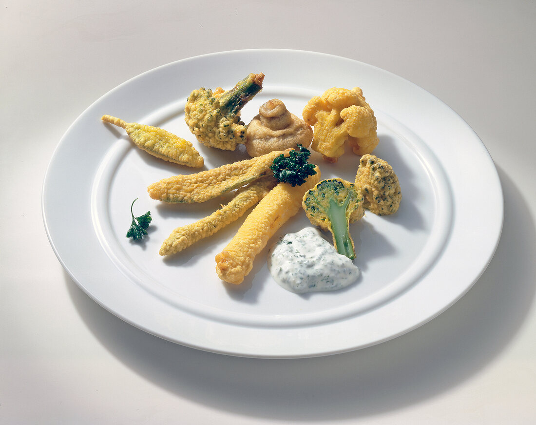 Vegetables with beer batter and dip on plate