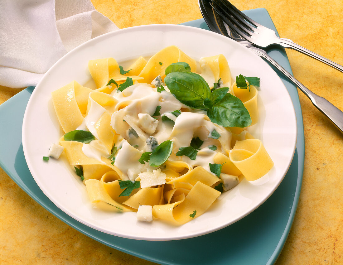 Ribbon pasta with cheese sauce and basil in bowl