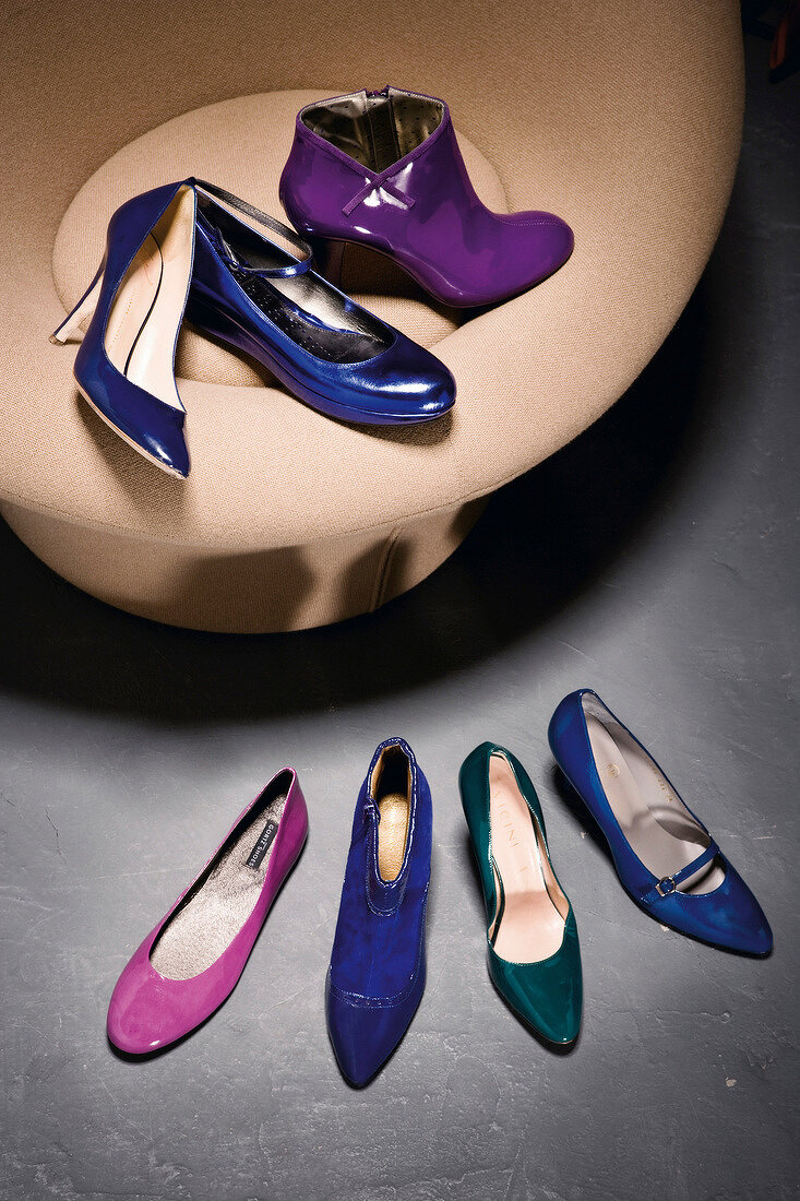 Patent leather shoes in blue, purple, pink and green colour on chair and floor