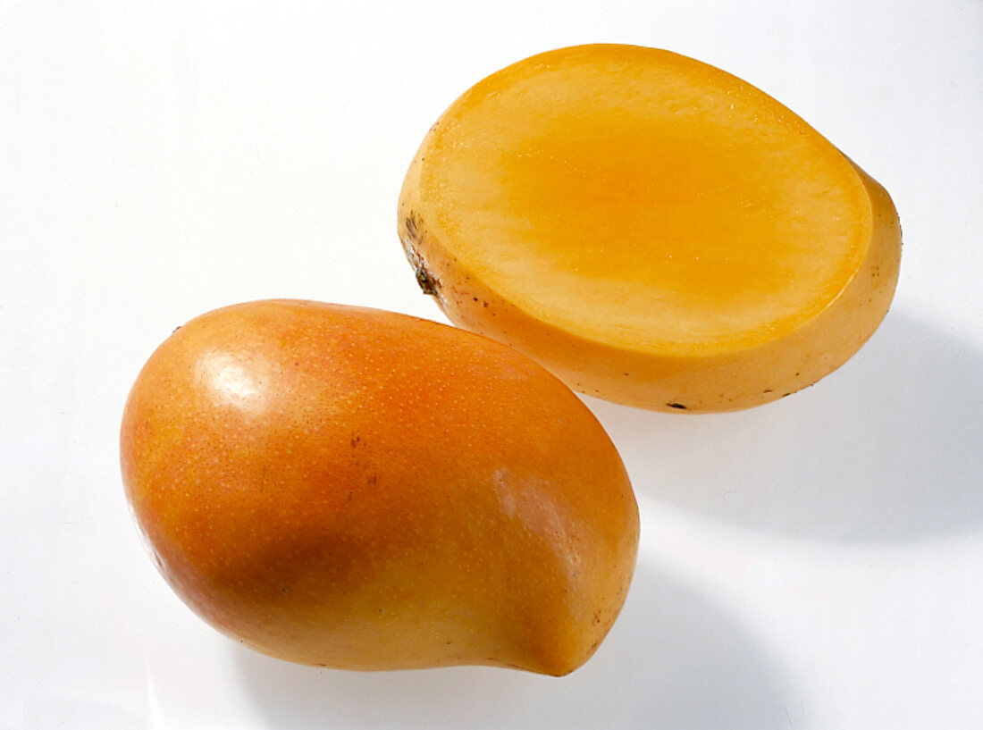 Whole and halved mango on white background