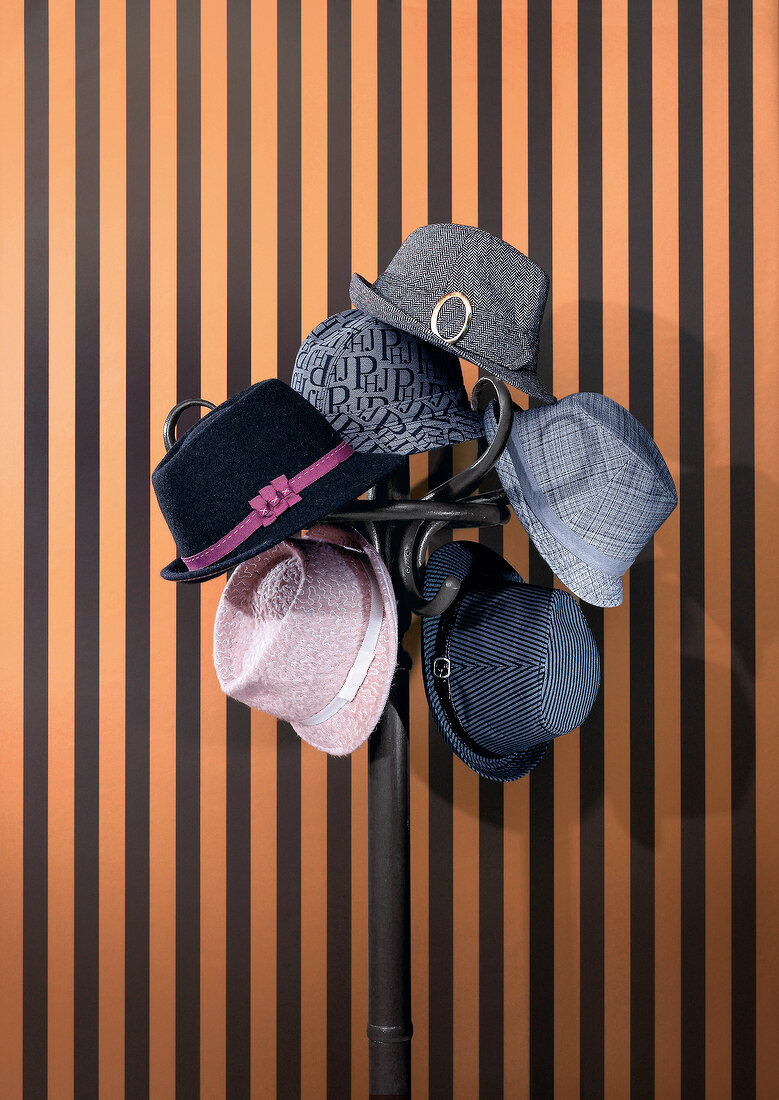 Colourful hats hung on coat rack against striped wall