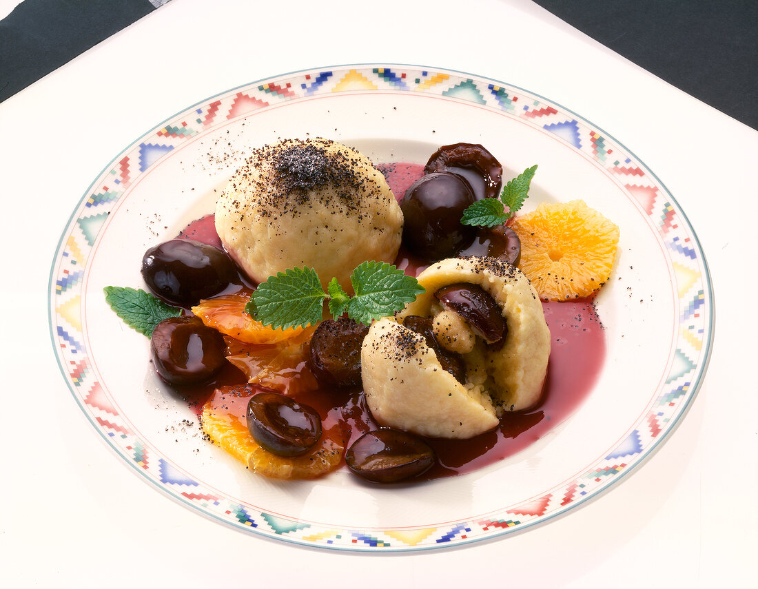 Plum dumplings with plums and oranges on plate