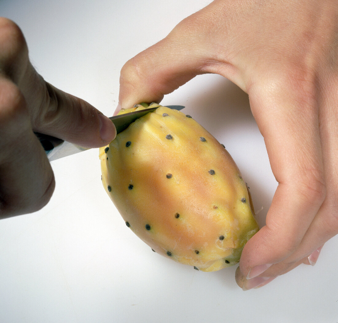 Sides of prickly pears being cut with knife, step 1