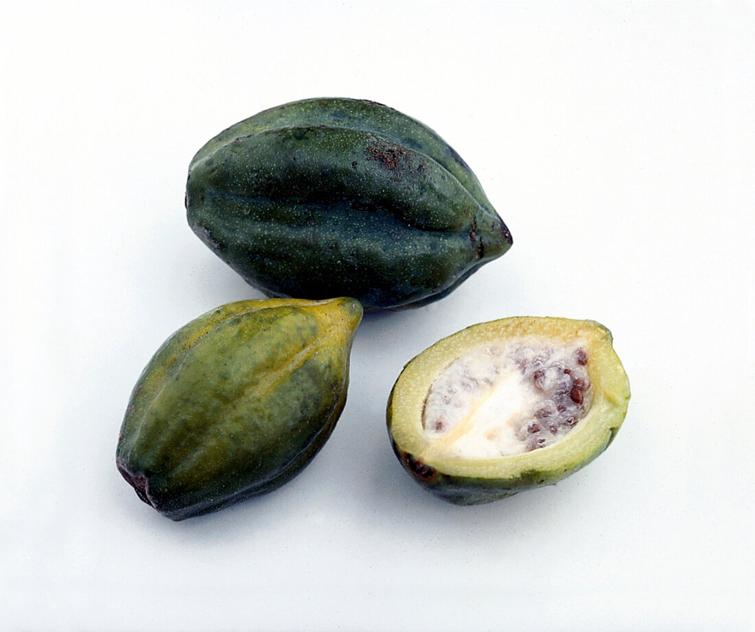 Whole and halved green papayas on white background