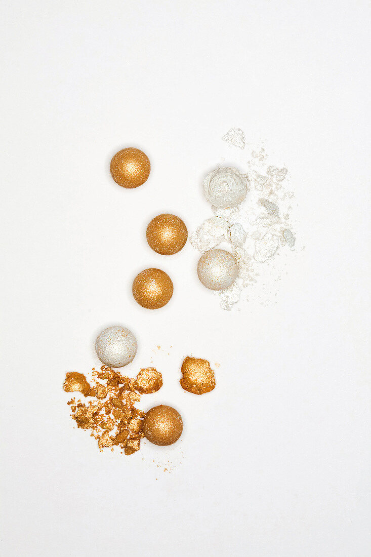 Gold and beige shiny mineral make-up balls on white background
