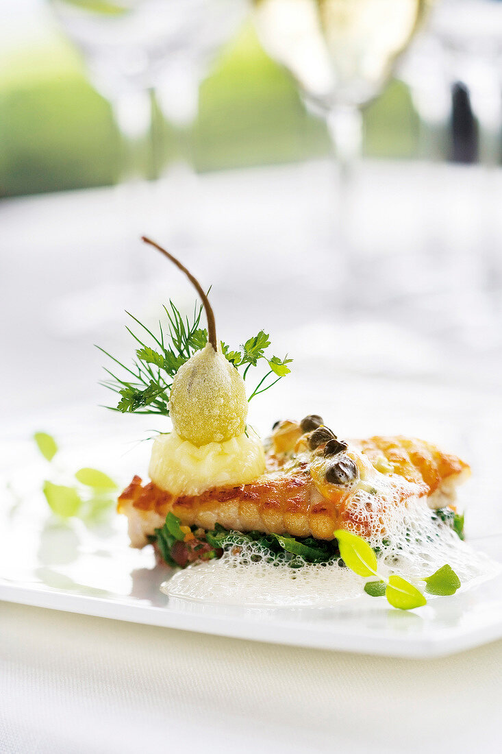 Skate wings with fried leeks, capers and lemon foam on plate