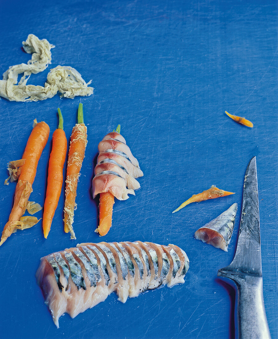 Carrot wrapped with mackerel slices on blue background