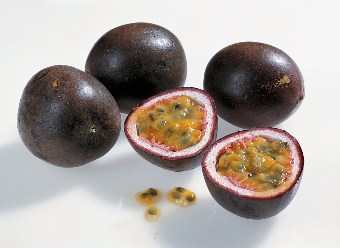 Whole and halved purple granadilla on white background