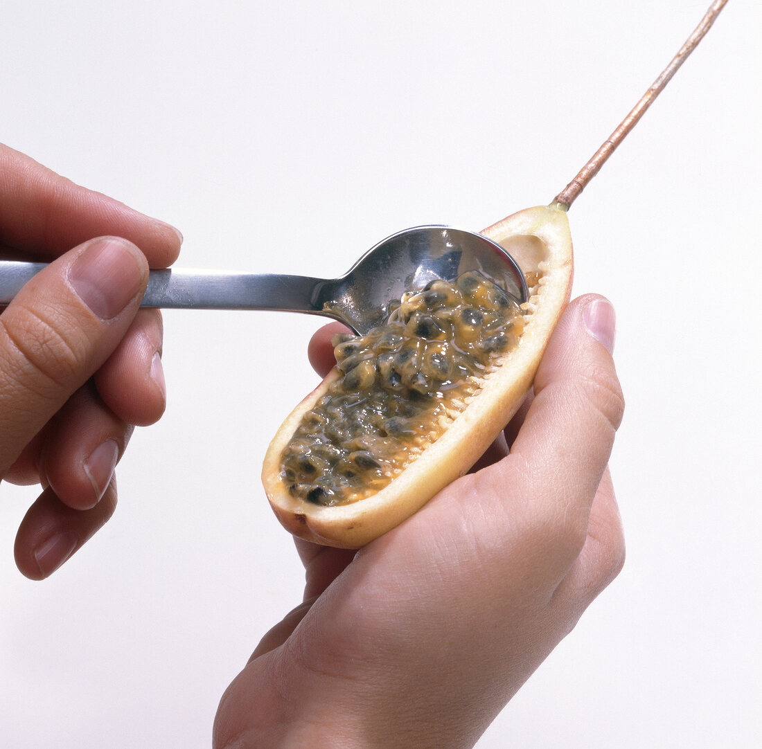 Scooping flesh of passion fruit with spoon, step 2