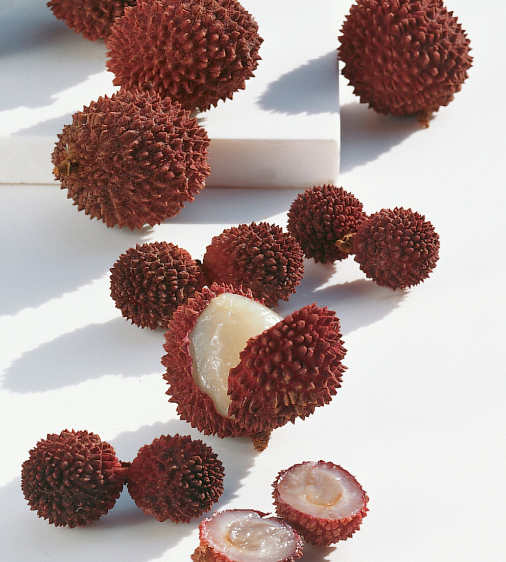 Whole and halved lychee on white background