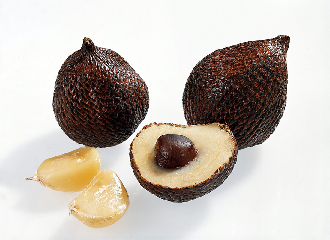 Halved and whole salak on white background