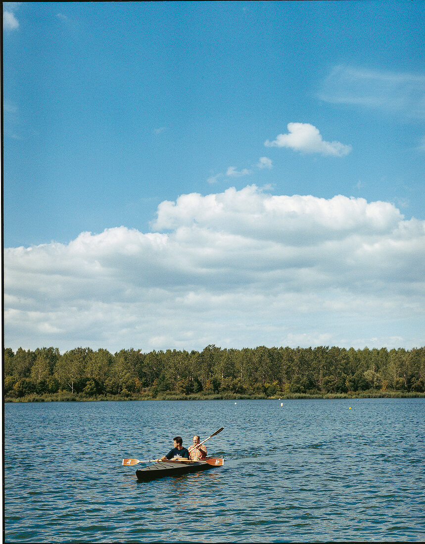 Two men rowing a flatboat in river