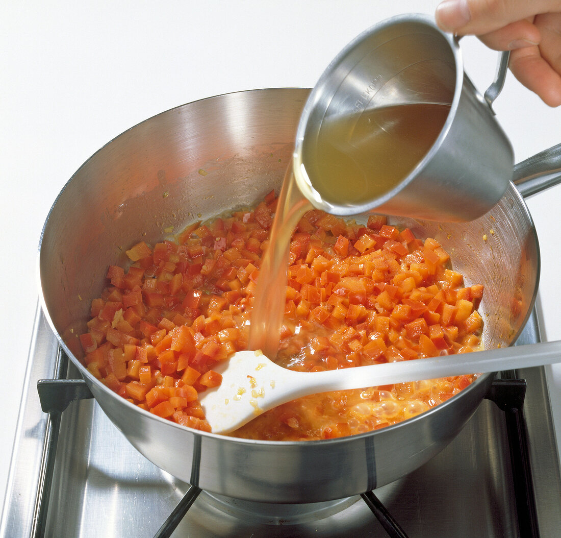 Adding stock to pepper mixture in pot, step 1