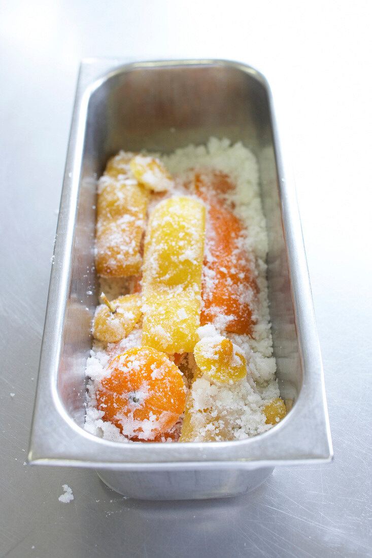 Various peeled citrus covered with icing sugar in a rectangular bowl