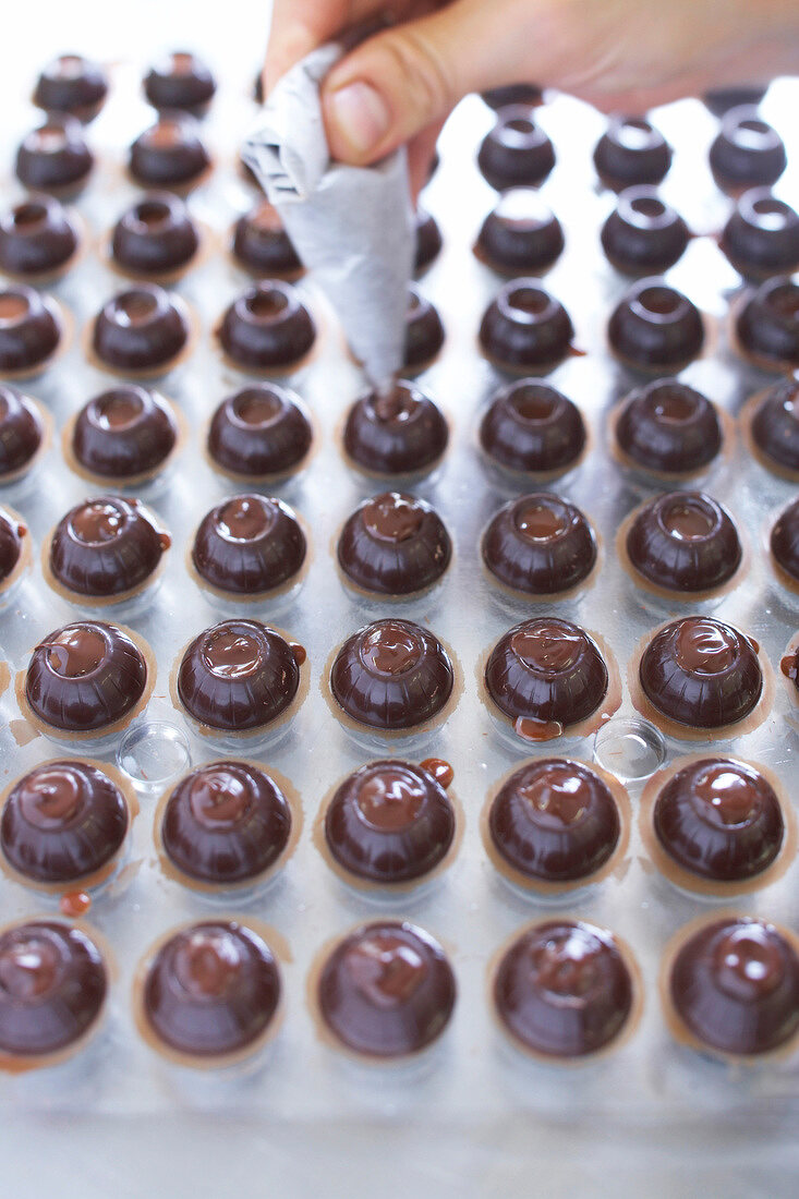 Close-up of chef filling ganache into hollow balls of chocolates