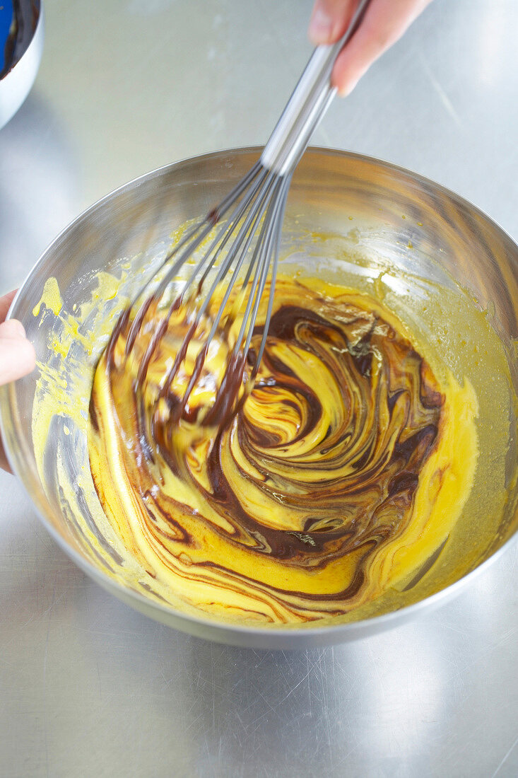 Mixed butter and cocoa being mixed with whisk for preparing chocolate parfait