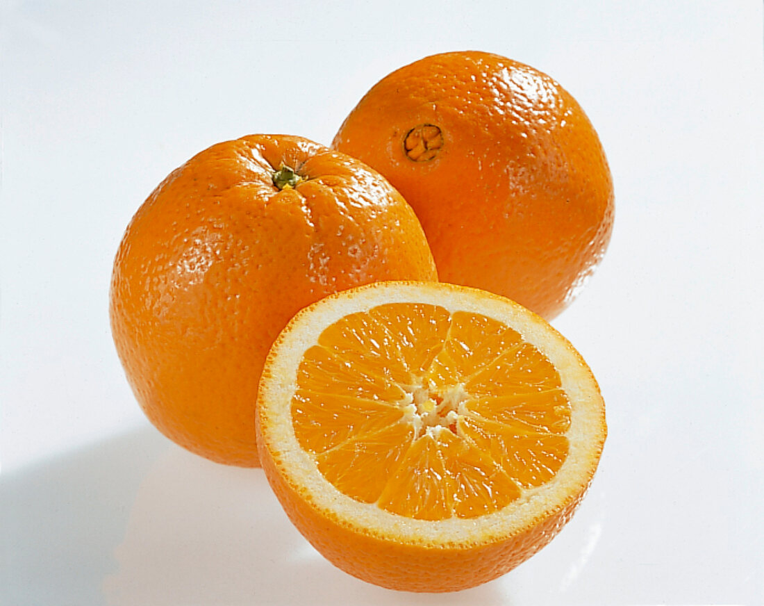 Half and whole oranges on white background