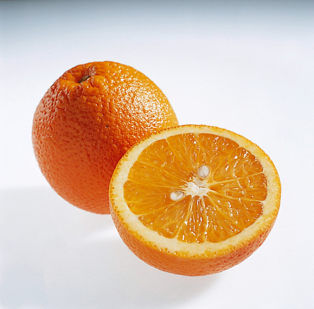 Halved and whole orange on white background