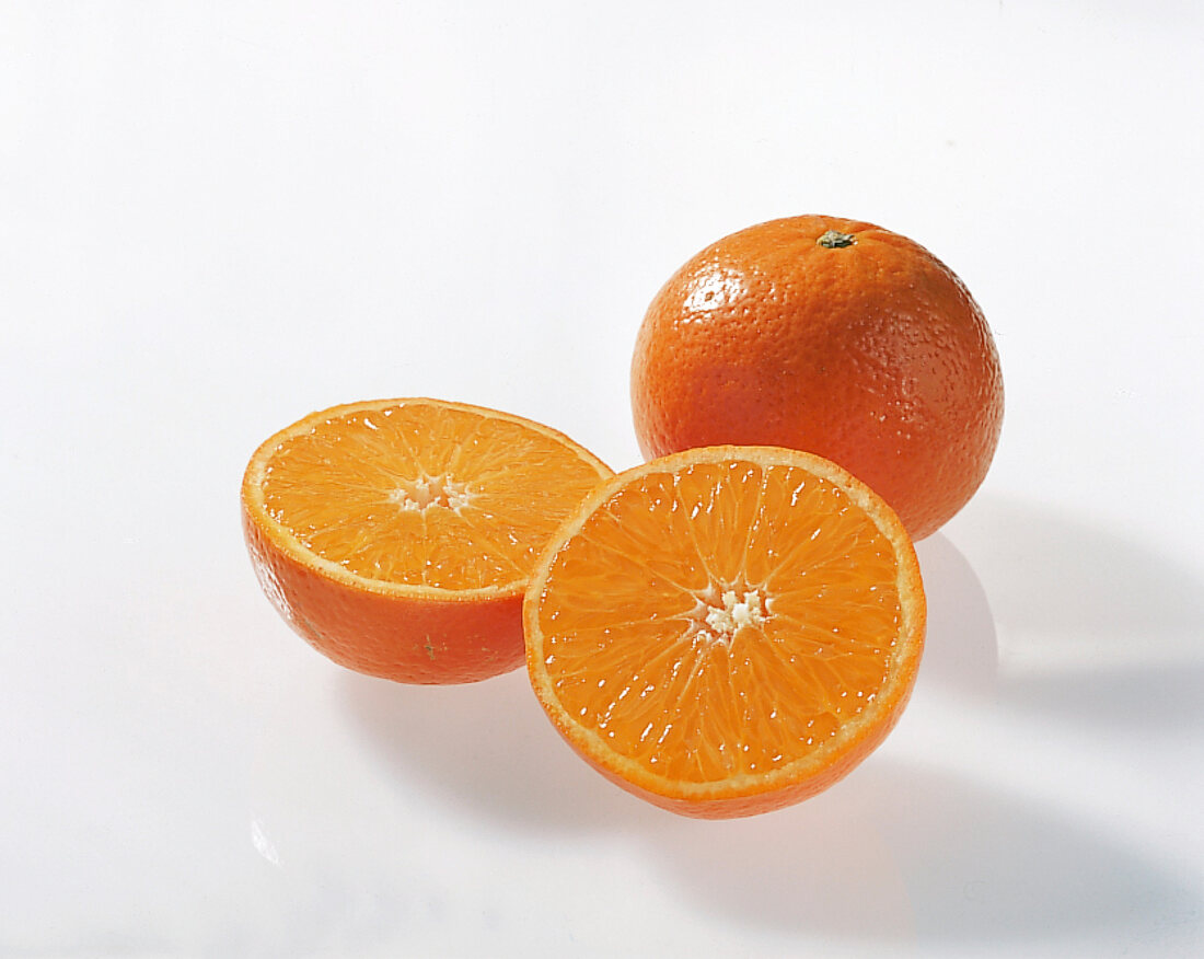 Halved and whole clementine's orange on white background