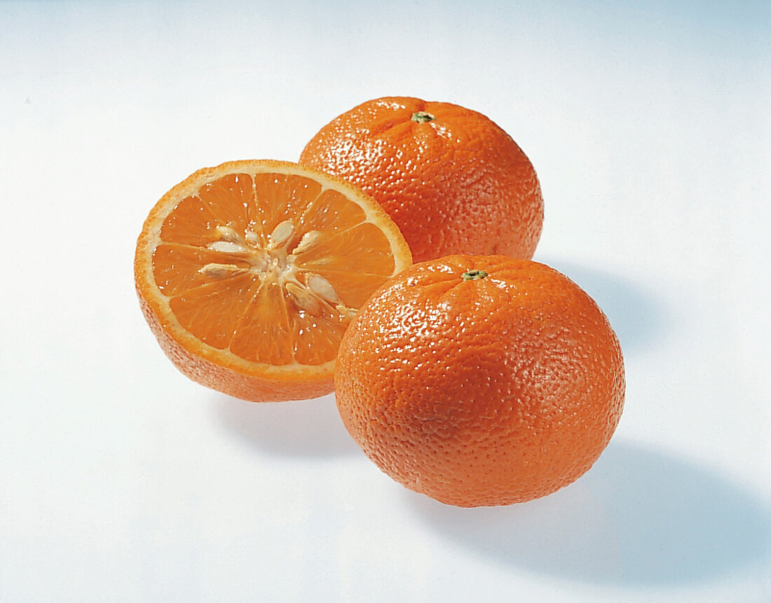 Halved and whole tangerine orange on white background