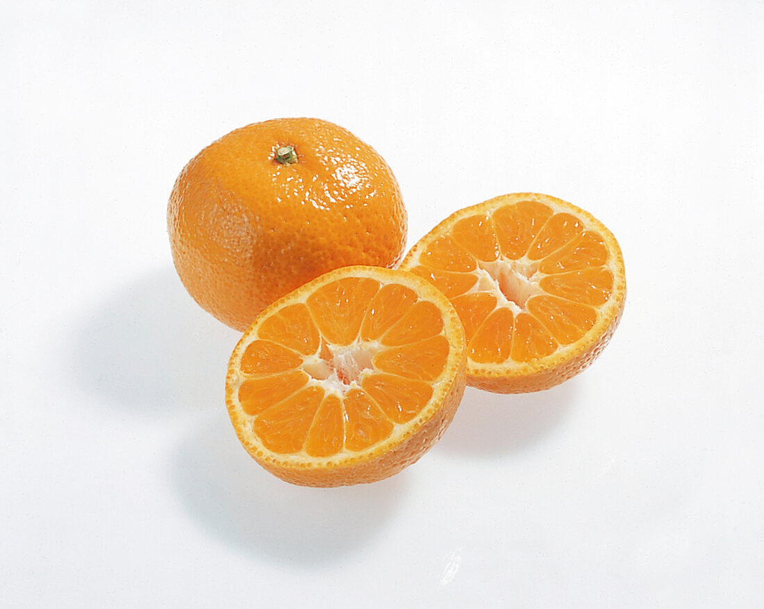 Whole and halved Satsuma orange on white background