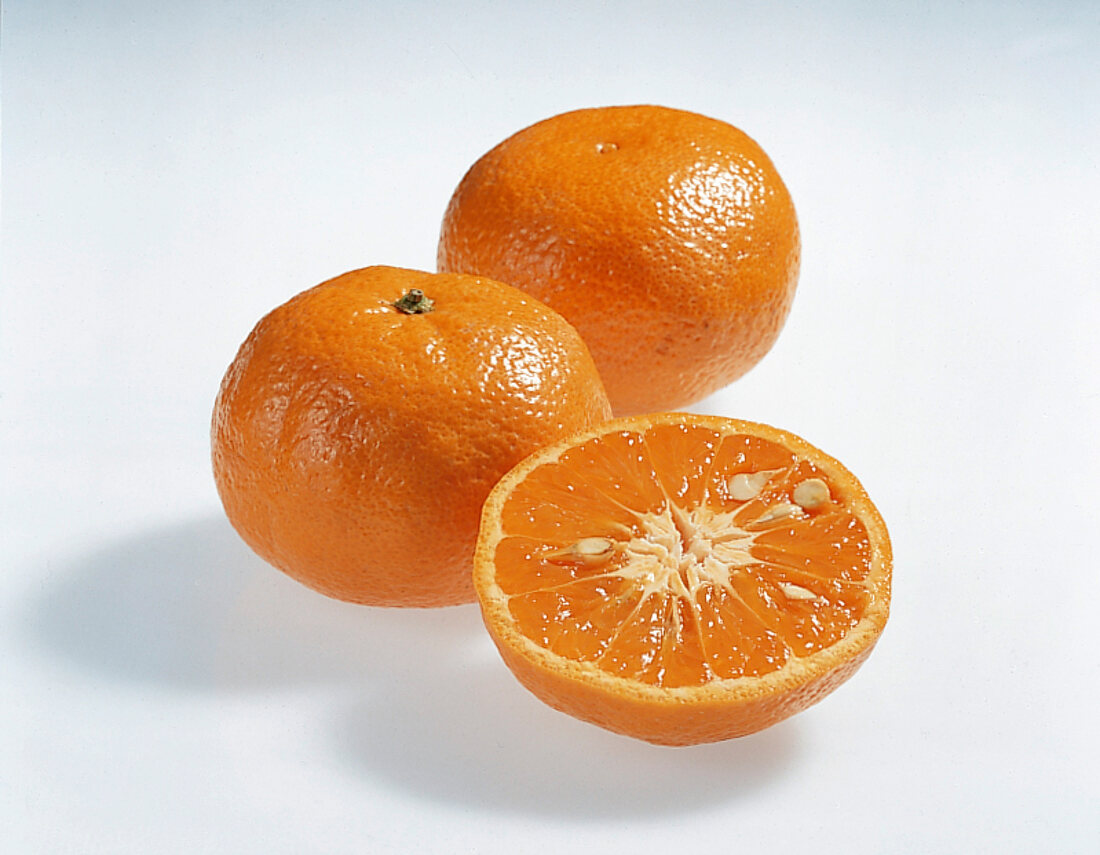 Whole and halved tangerine orange on white background
