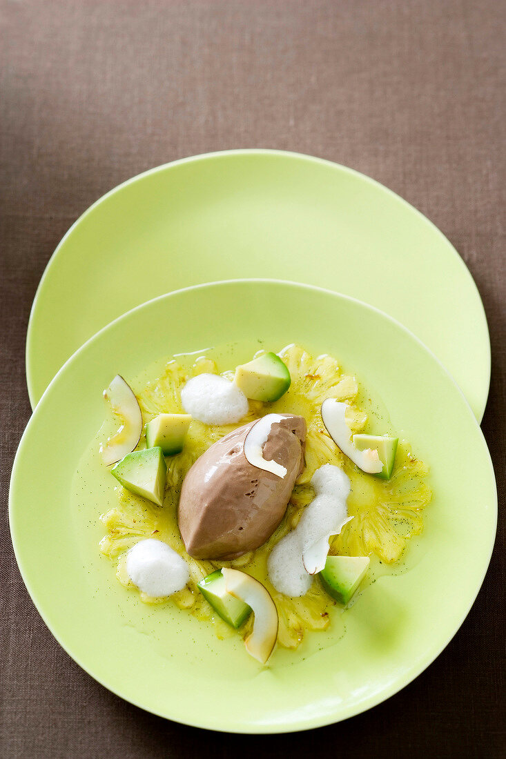 Chilli chocolate ice with avocado, rum foam and pineapple carpaccio served on plate
