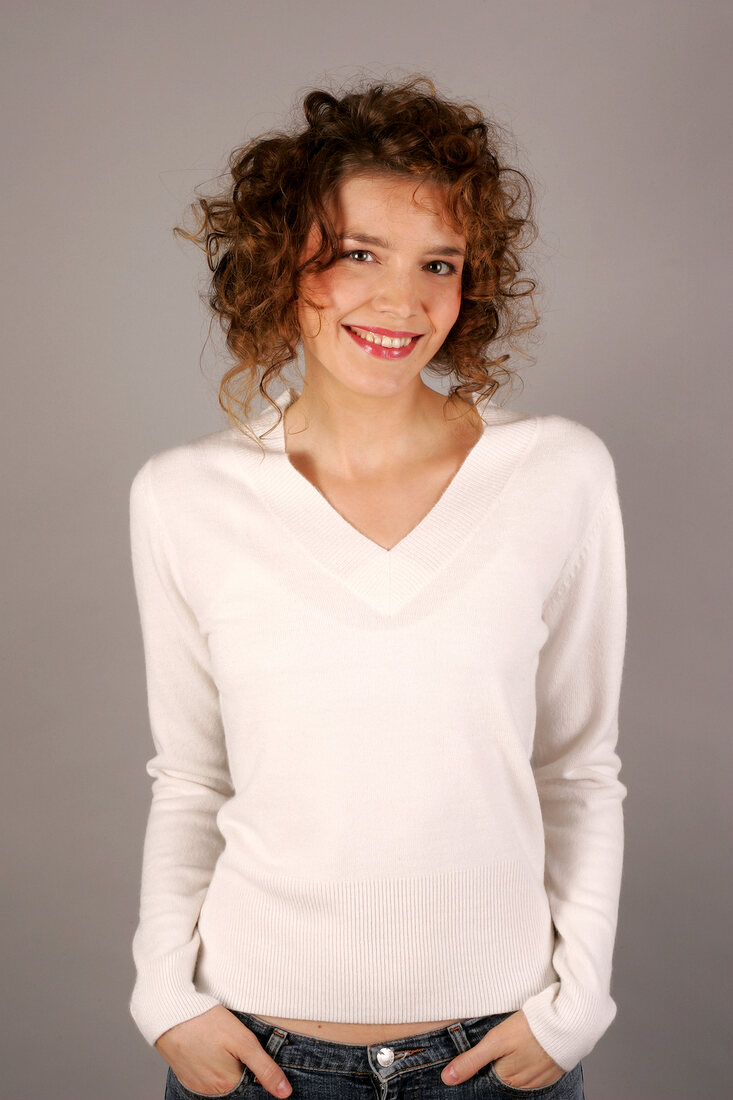 Portrait of beautiful woman with curly hair wearing white sweater, smiling widely