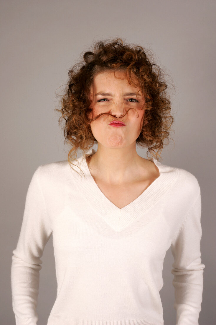 Frau mit weißem Pullover Strähne zwischen Nase und Mund