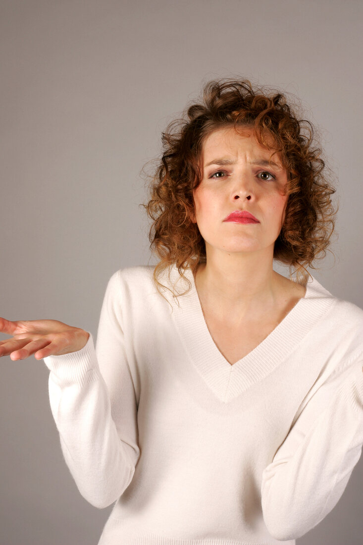 Portrait of sad woman with curly hair wearing white sweater