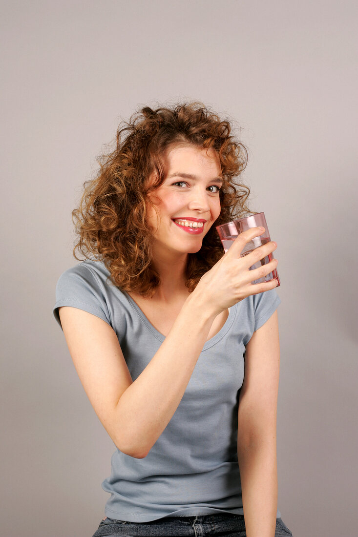 Woman drinking glass of water, smiling