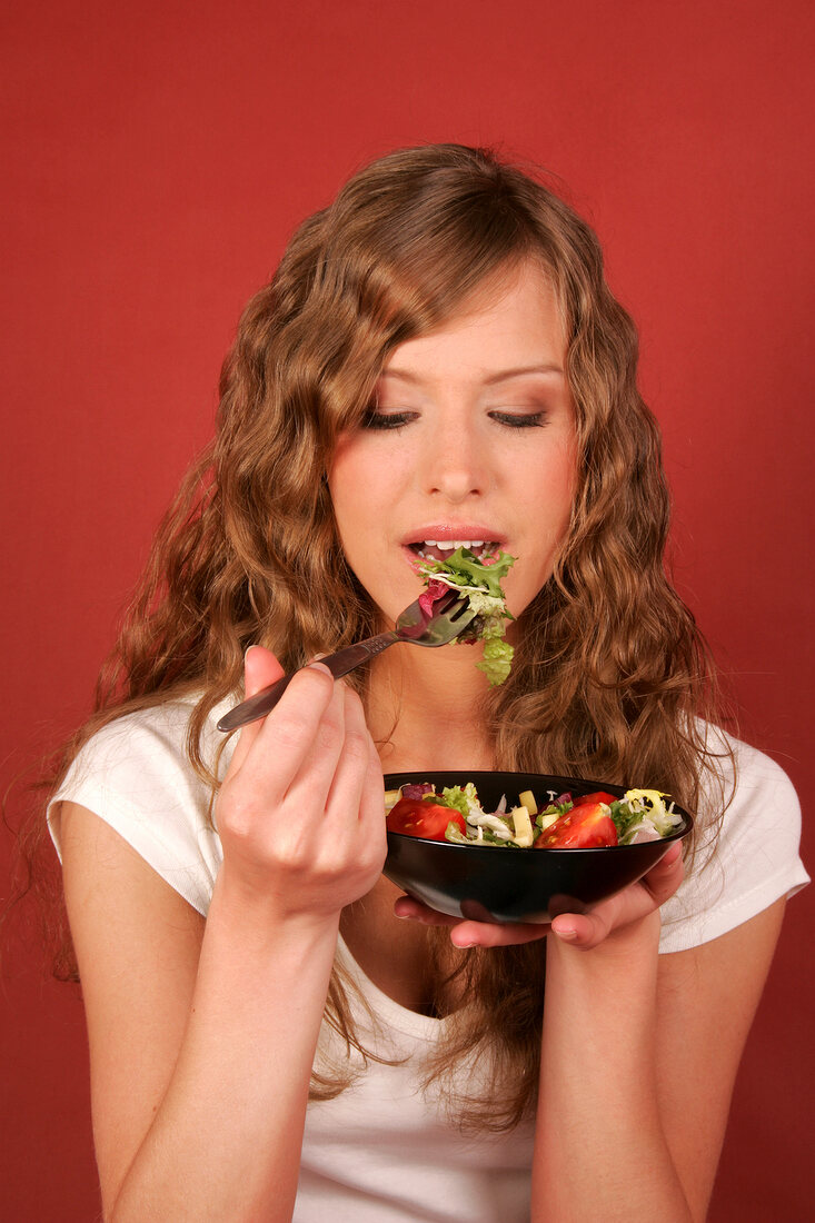 Pretty woman holding bowl of salad and fork, smiling