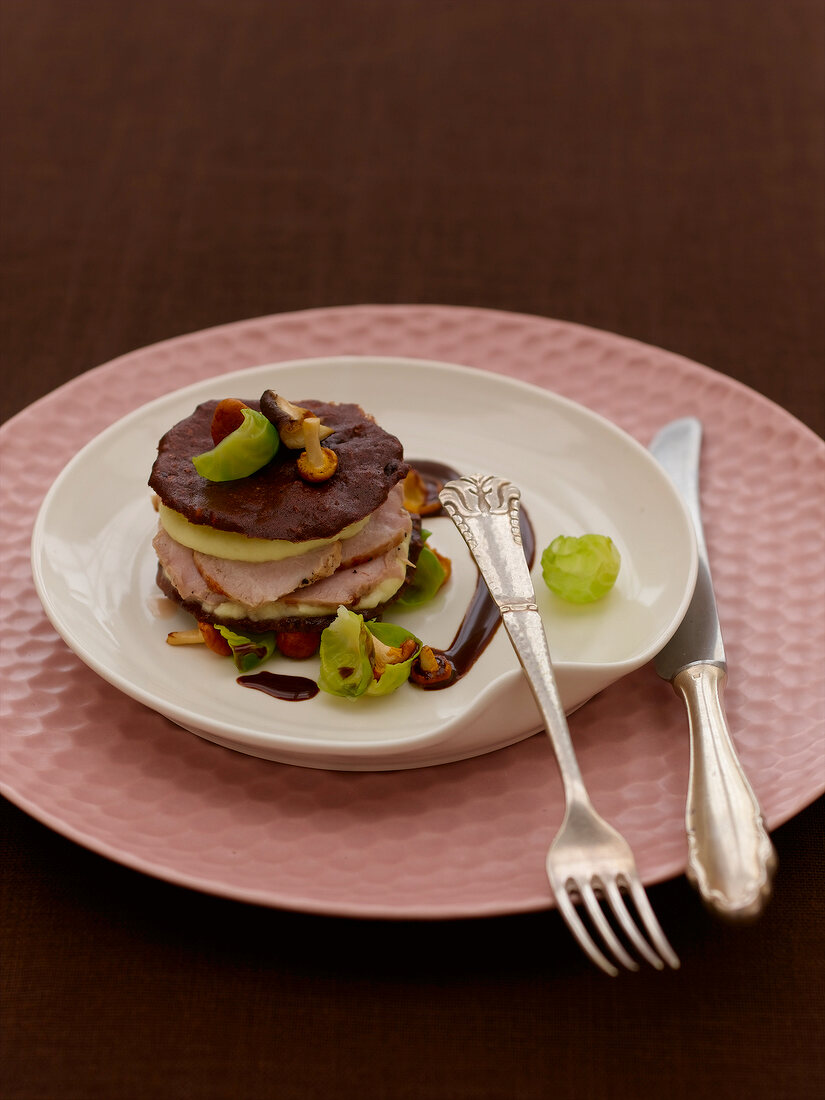 Boar with brussels sprout leaves and chocolate nut millefeuille on plate