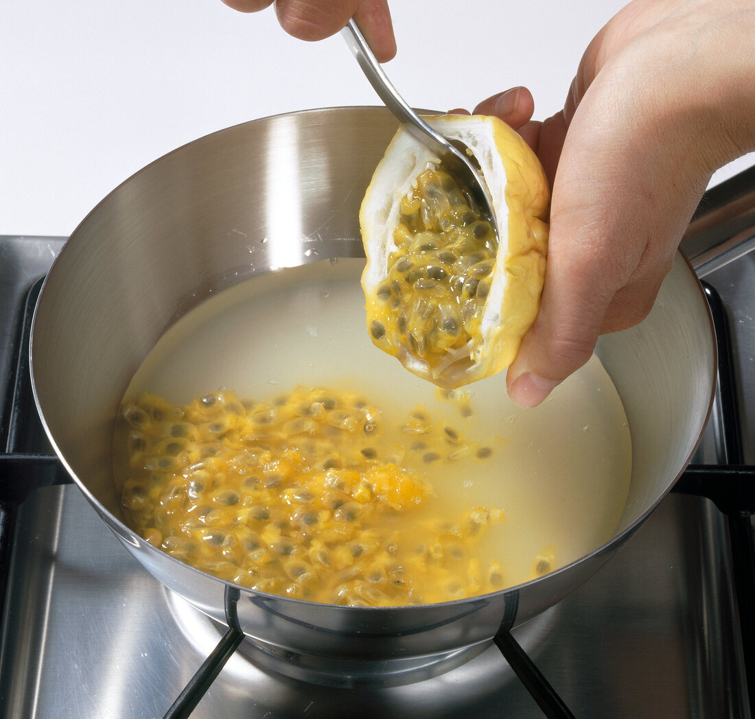 Close up of hand adding pulp from passion fruit in pot