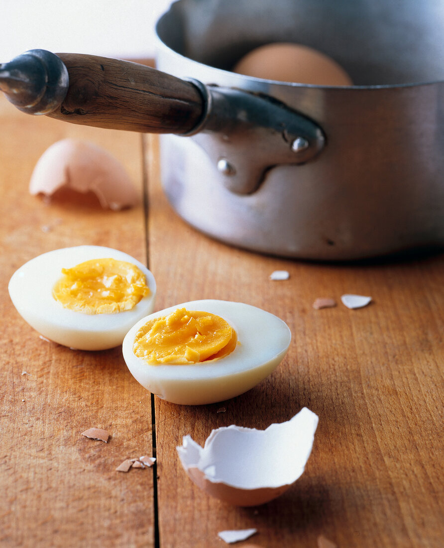 Egg halves with broken egg shell and egg in pot